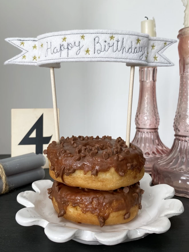 Star Banner Cake Topper in chocolate doughnut on plate with candlesticks and number 4 in background
