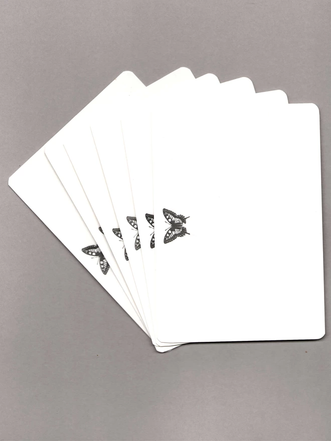 Six notecards with a black butterfly at the top laid out on a grey background