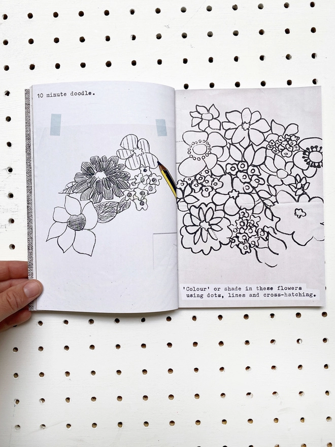 open book with instructions, flower drawings and aged paper pages on white pegboard 