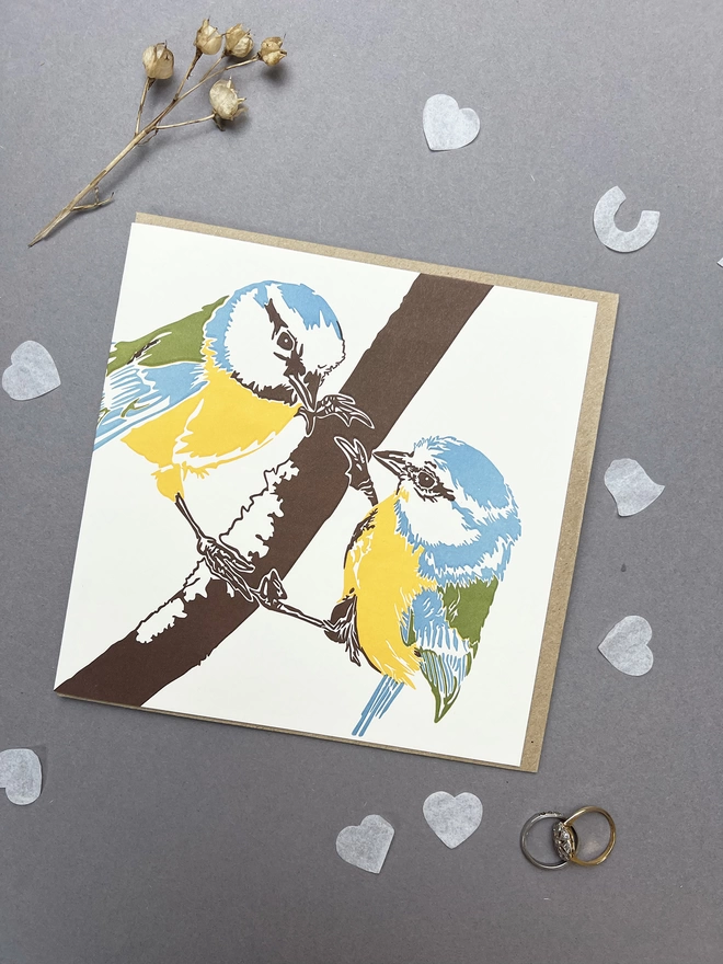 Letterpress print of two blue tits in love, perched on a branch. The birds and lovely bold colours of yellow, green and blue.