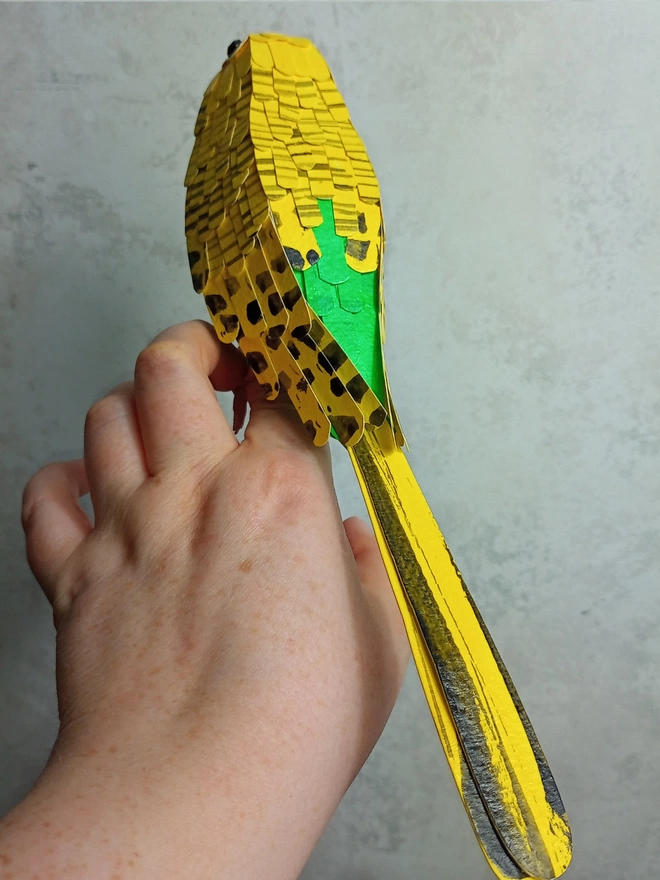 back side of a yellow and green budgie sculpture