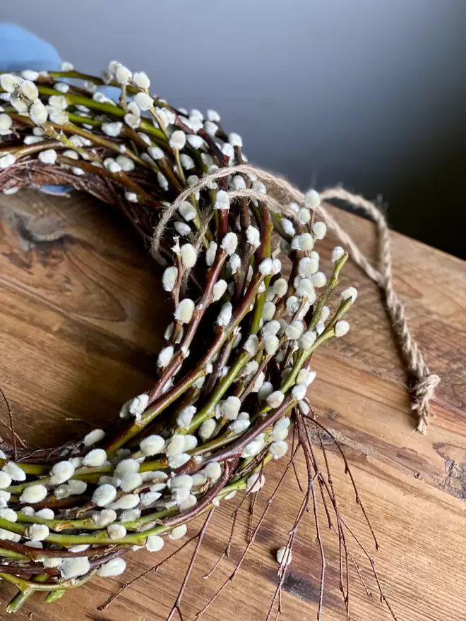 pussy willow wreath placed on rustic table with jute twine