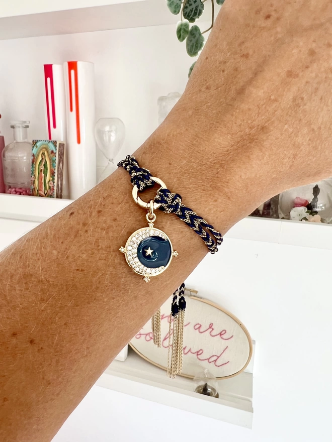 Woman's wrist wearing a navy and gold chain friendship bracelet with a navy enamel crescent moon charm