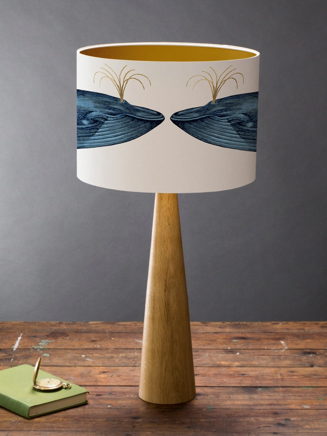 Drum Lampshade featuring the Blue Whale on a wooden base on a shelf with books and ornaments
