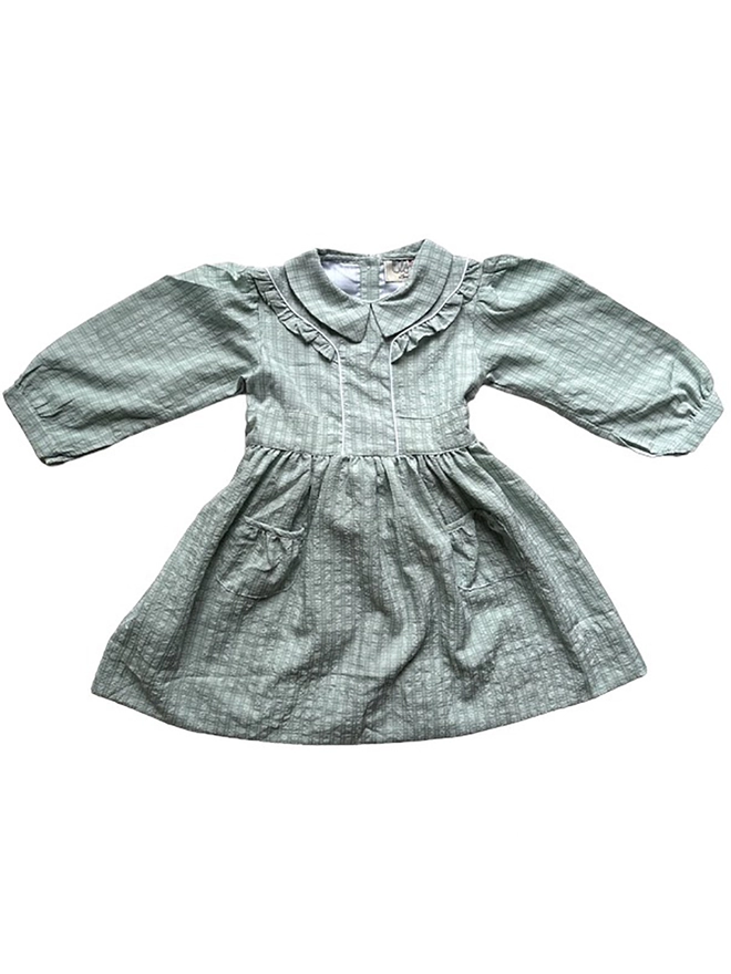 Long sleeved green checked dress with ruffle detail at shoulder, peaked peter pan collar and patch pockets.