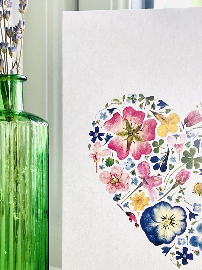 Close-Up of Greetings Card Detail Showing Pressed Flowers Heart Design - Standing on Windowsill Next to Green Glass Bottle with Dried Lavender