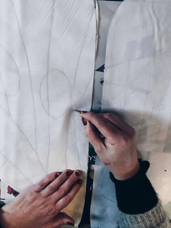 hands drawing a butterfly wing pattern on white fabric