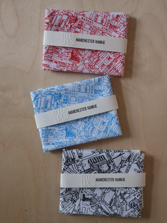 Three folded Mr.PS Manchester map hankies to show the colour options available: red, sky blue, and charcoal grey