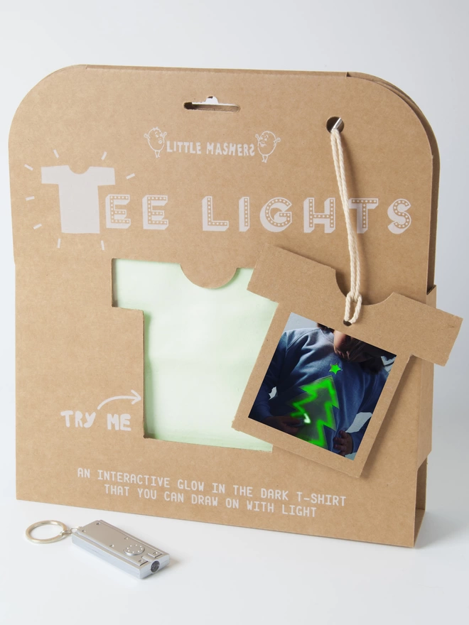 Kraft packaging with a tshirt hole cut out showing a xmas tree glow in the dark jumper