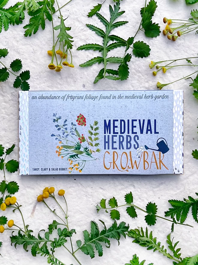 The Medieval Herbs Growbar on a background of yellow tansy flowers and salad burnet leaves. 