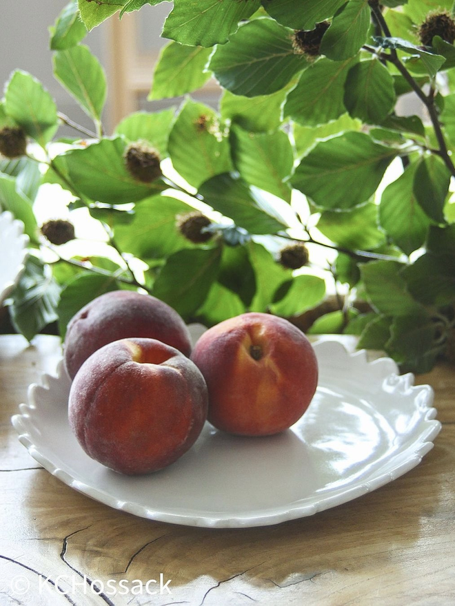 white fiore edge serving bowl with peaches and hazelnut in background