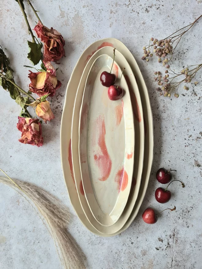 Oval serving platter, serving dish, ceramic dish, pottery dish, serveware, tableware, easter, Jenny Hopps Pottery, pink, cream, white, photographed on grey background with cherries and dried flowers