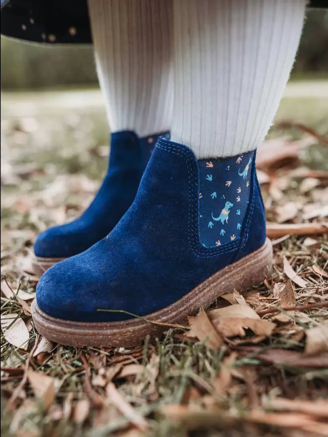 Little girl wearing Navy suede chelsea boots with a blue dinosaur print