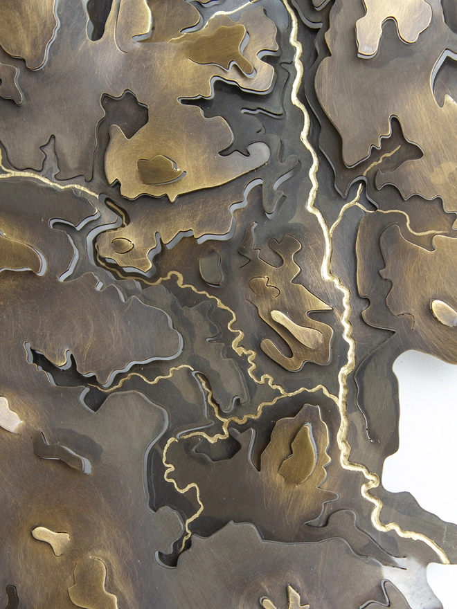 close up of the hand engraved rivers on the brass Peak District contour map