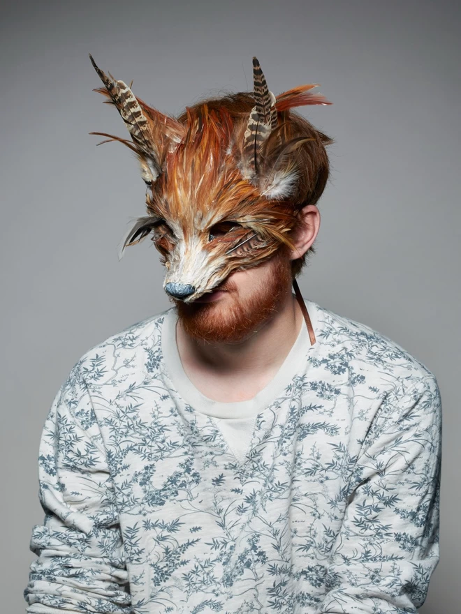 Man wearing a luxury red fox masquerade mask over his face