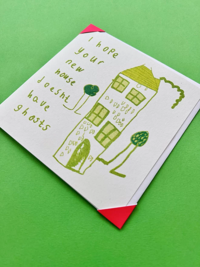 Close up I Hope Your New House Doesn't Have Ghosts card with a simple house & garden in bright greens