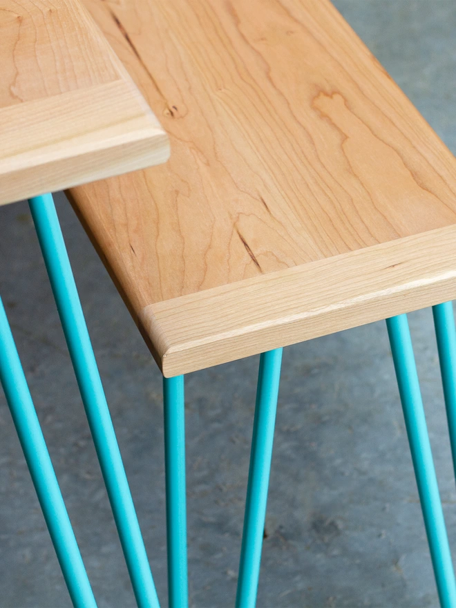 angled corner view of a hairpin leg dining table and benches with cherry wood tops and duck egg blue hairpin legs