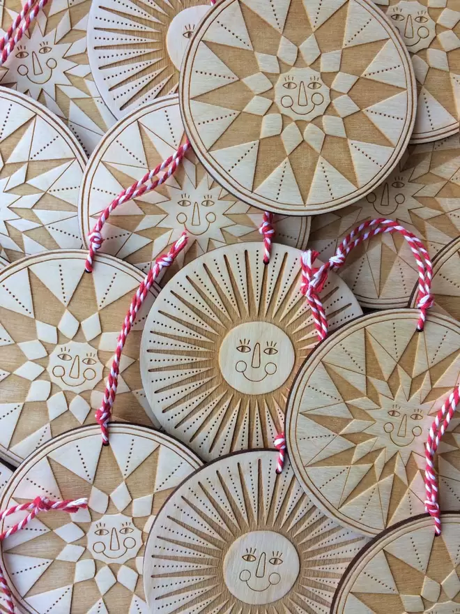 Lots of the engraved wooden happy stars are laid out and threaded with red and white twine 