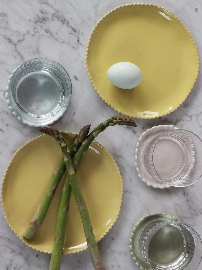 yellow scalloped edge plates with asparagus and water glasses