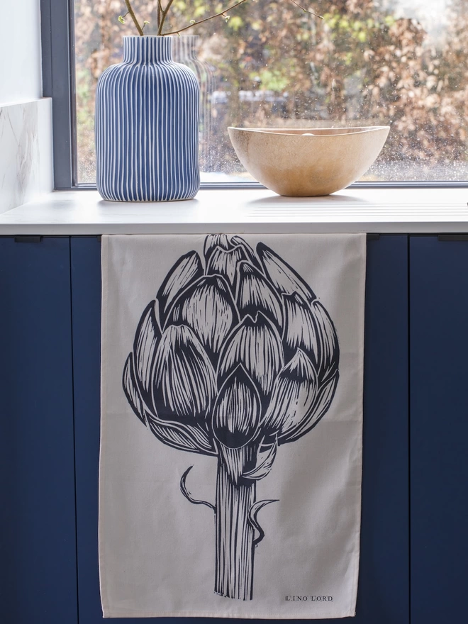 Picture of a tea towel in a kitchen with an image of an artichoke, taken from an original lino print