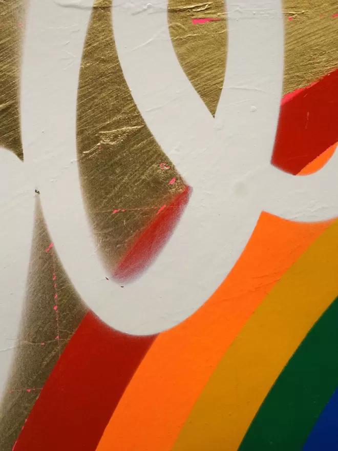 Close crop of gold leaf with white writing and colourful rainbow