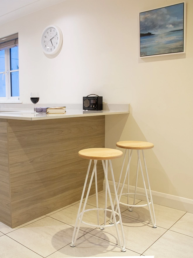 pair of hairpin leg bar stools against a kitchen counter, with white hairpin legs and ash seats