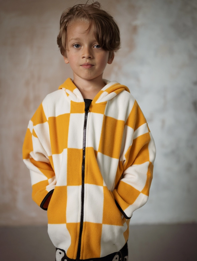 Another Fox Orange Checkerboard Polar Fleece Kids Hoody seen on a child with their hands in the pockets.