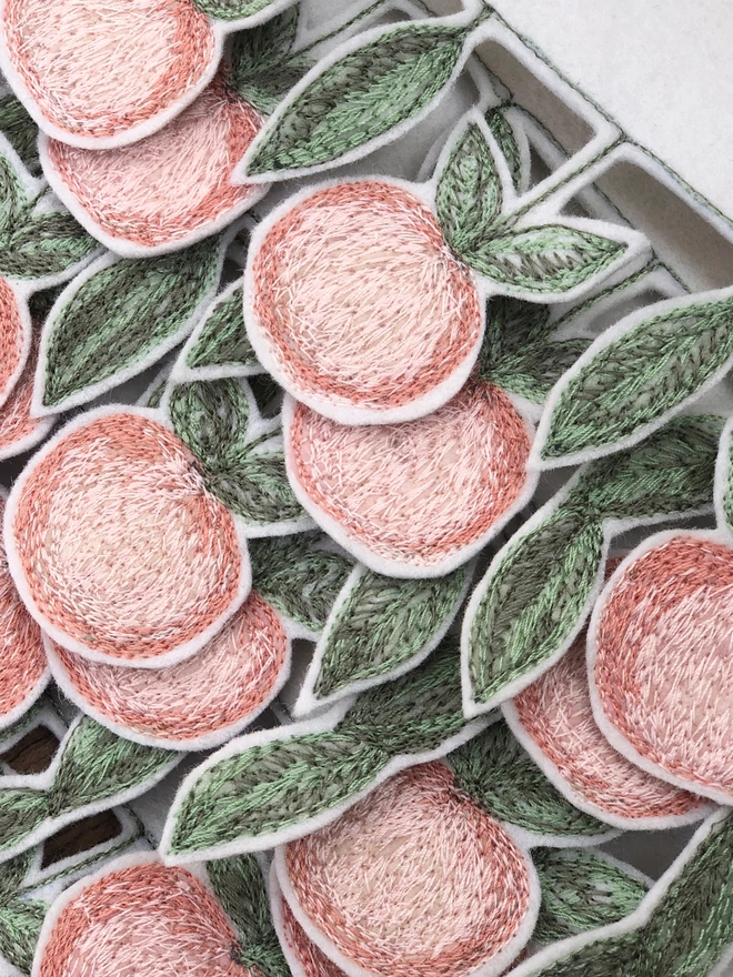 Close up of embroidered peach tassel on everything's peachy banner.