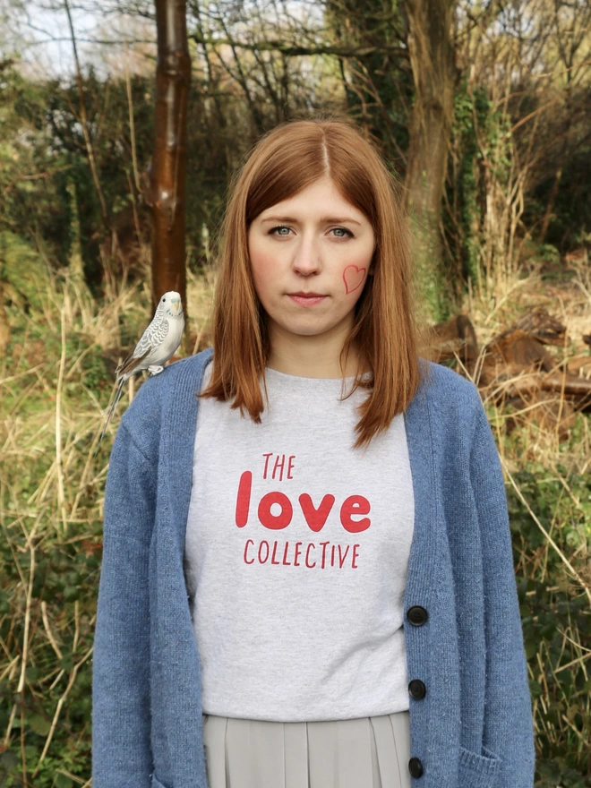 Girl with bird on shoulder wearing screen printed The Love Collective tee