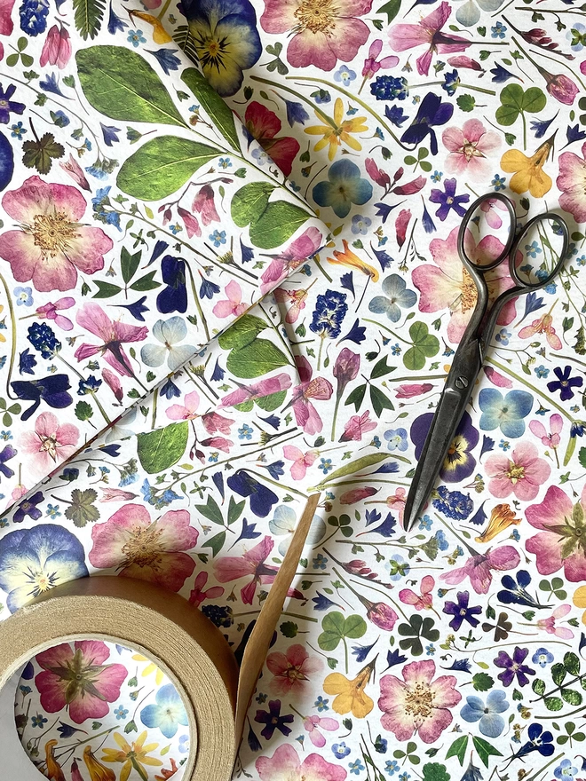 Recycled floral wrapping paper sheet with vintage scissors and brown paper tape