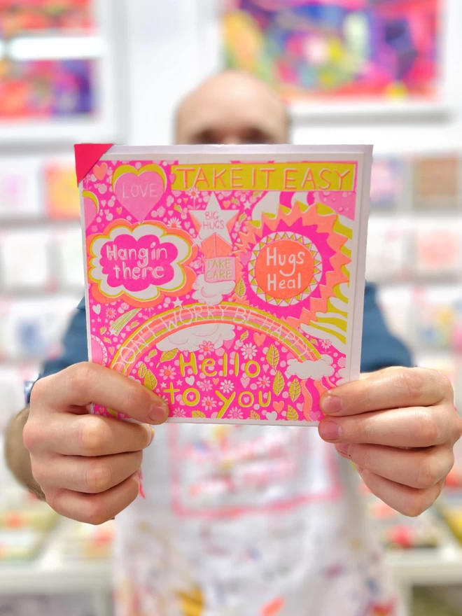 Artists holding Take it Easy card, a riso printed get well soon card showing messages of positivity