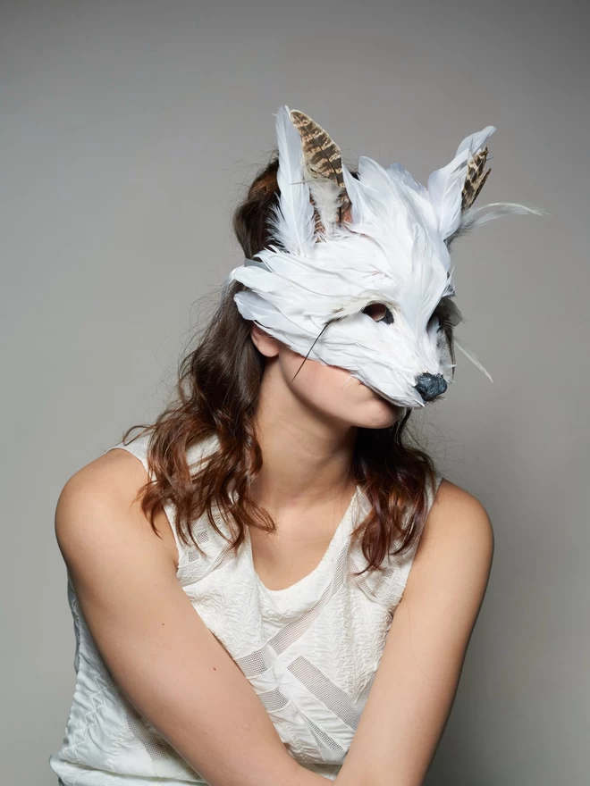 Woman wearing luxury white fox masquerade mask down over her face
