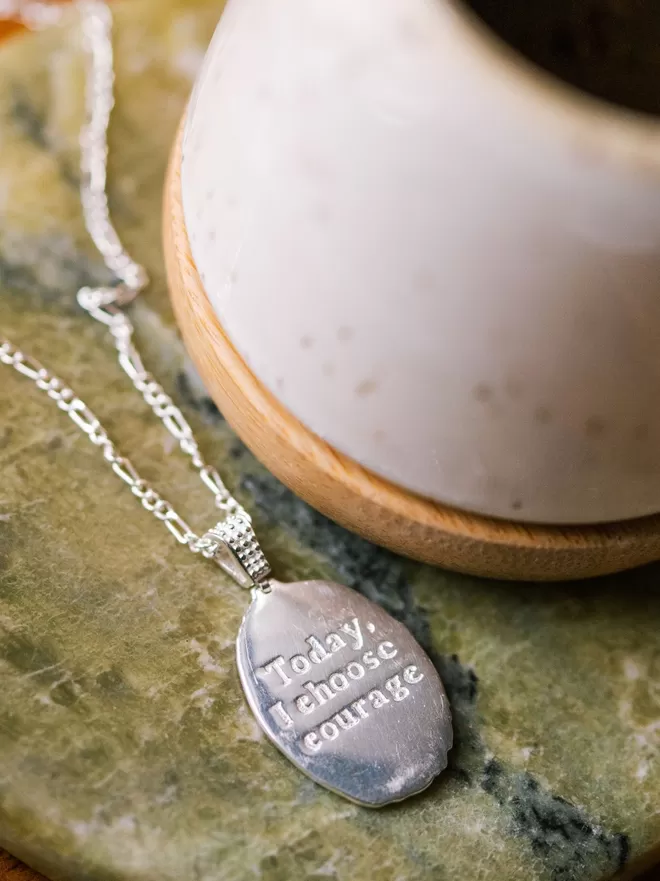 Oval necklace with Today I choose courage message engraved on reverse on green marble background