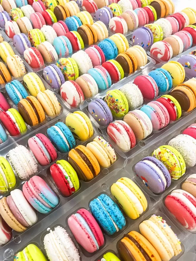 an assortment of colourful macarons in a clear tray
