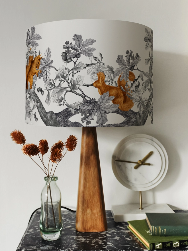 Drum Lampshade featuring Red Squirrels on a wooden base on a shelf with books and ornaments