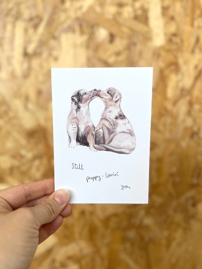 a greetings card featuring two puppies kissing each other with the wording “Still puppy-lovin’ you”