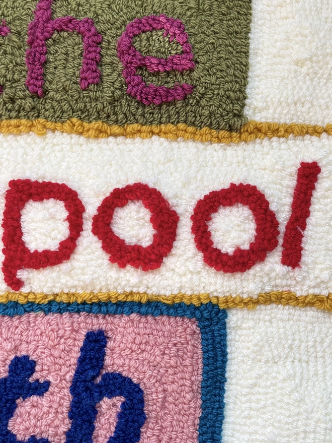 lettering made of woollen tufts in bright colours