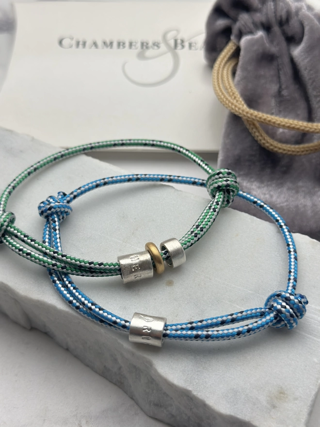two men's personalised sterling silver bead friendship bracelets. one on blue cord, the other on green