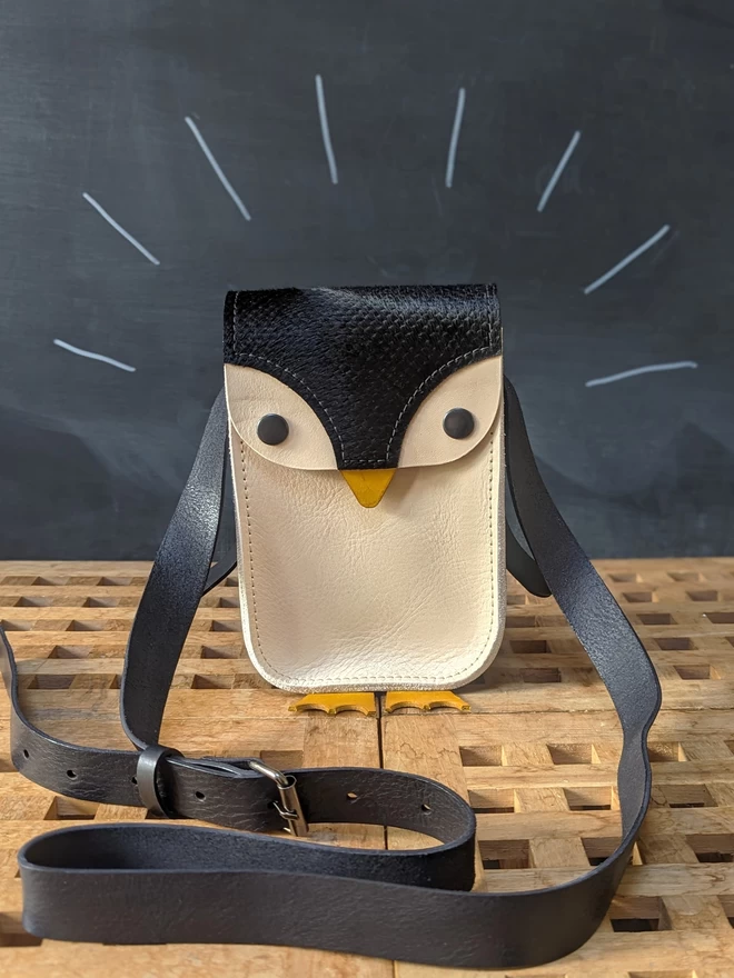 Front view of handmade leather penguin cross- body bag, showing adjustable strap.