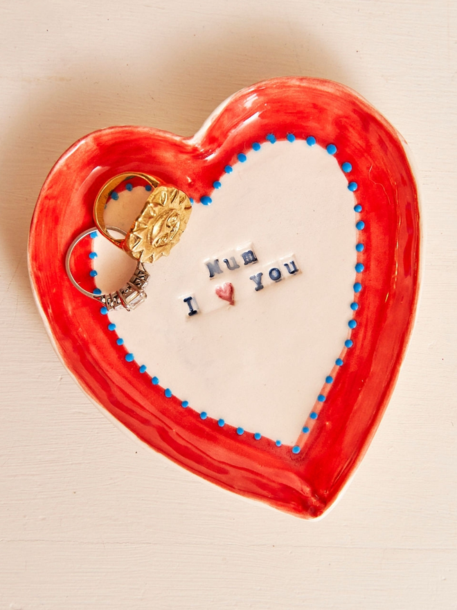 Heart shaped ceramic dish with the words Mum I (heart symbol) You. decorated with a red border with blue dots. Perfect for a Mother's Day Gift