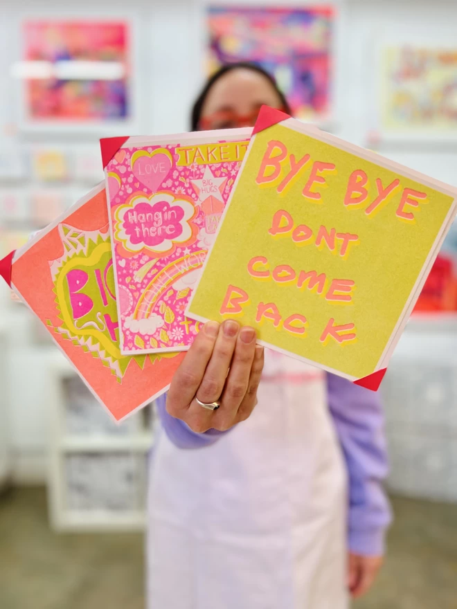 Artist holding Bye Bye Don't Come Back card with words printed in orange on lime green background