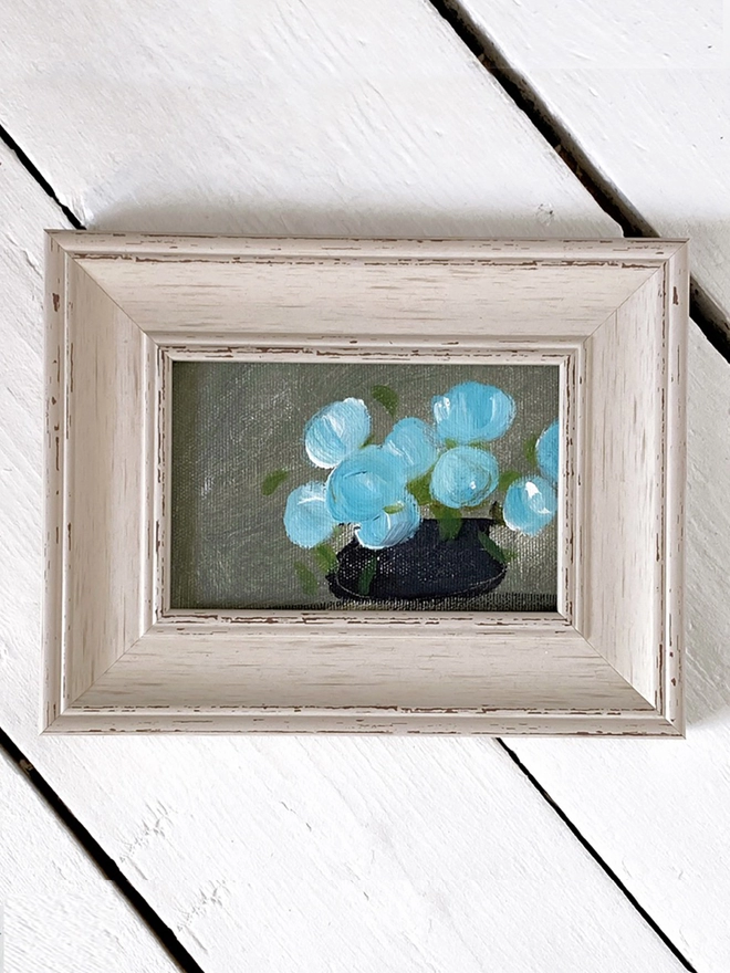 painting of blue flowers in rustic cream frame