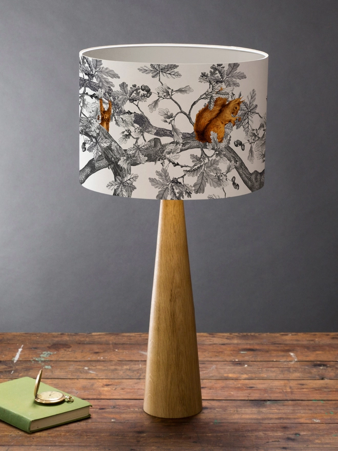 Drum Lampshade featuring Red Squirrels on a wooden base on a shelf with books and ornaments