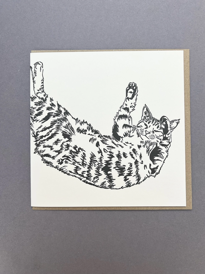 Black and white tabby car stretching over the front of the big card