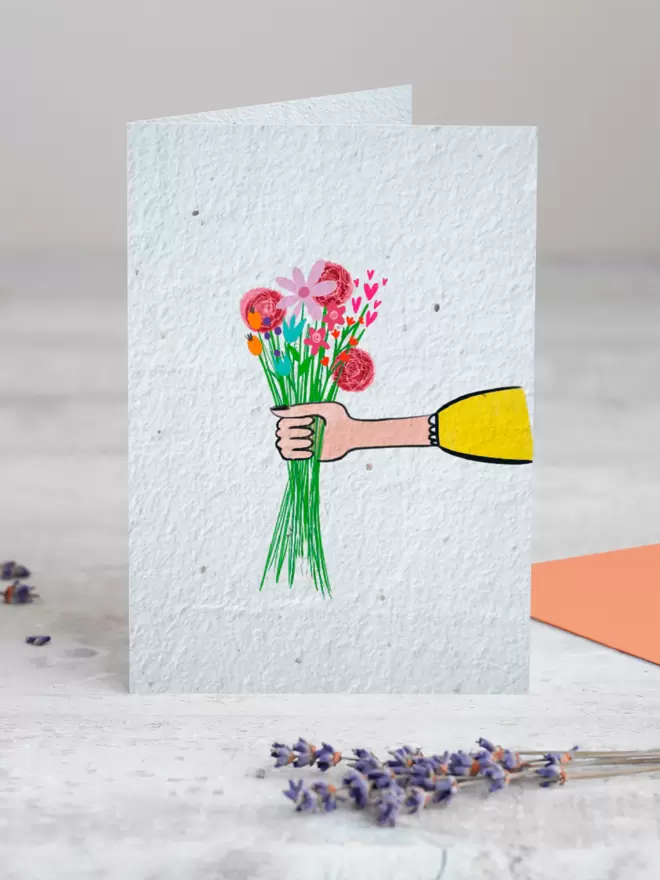 Seeded Paper Greeting Card with an illustration of a hand holding out a bouquet of flowers  with a sprig of Lavender placed in the foreground of the image