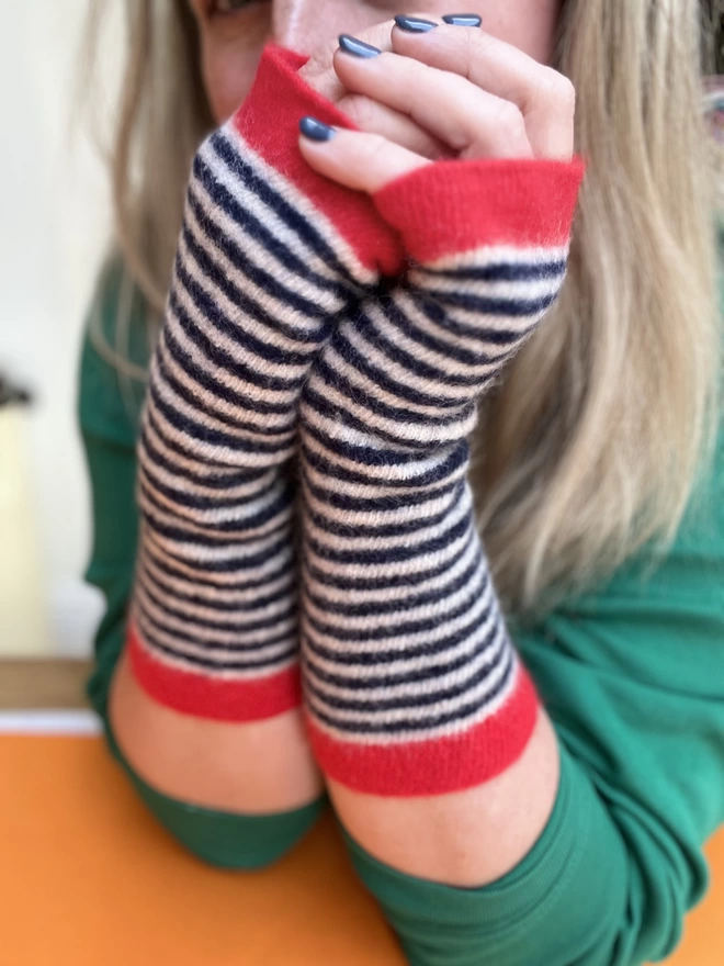 Knitted red navy striped wristwarmers being worn showing length