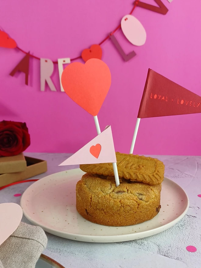 A heart and two paper flag decorations placed into a large cookie.