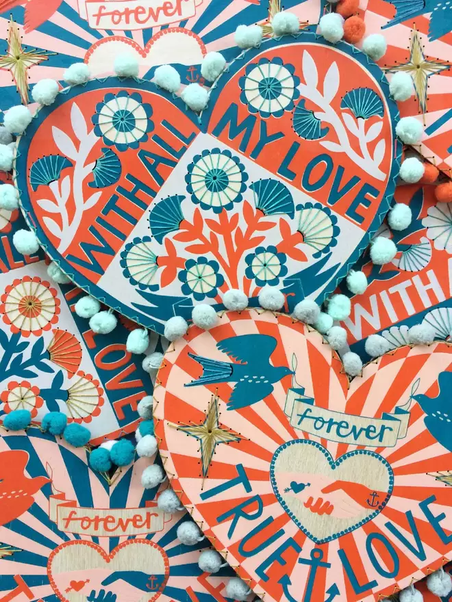 A stack of unique and colourful valentine hearts are spread out, printed with romantic messages
