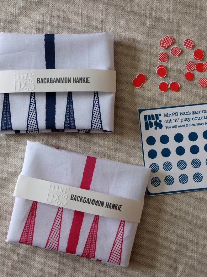 2 folded Backgammon Hankies, 1 in raspberry and 1 in midnight blue with a cut out counters card, and some red counters already cut out.