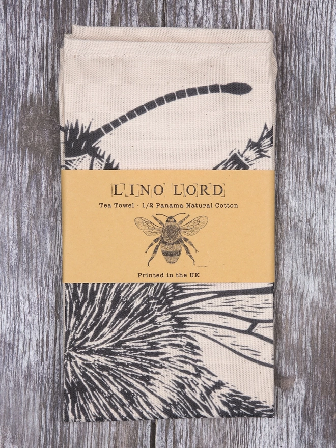 Picture of a folded tea towel with an image of a bee, taken from an original lino print